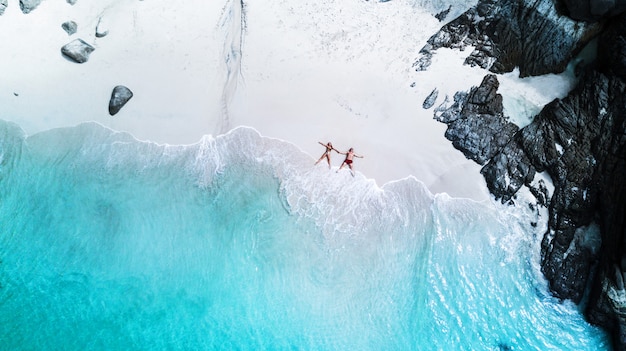 Foto praia drone vista ilha tropical, praia branca com ondas, casal deitar na praia