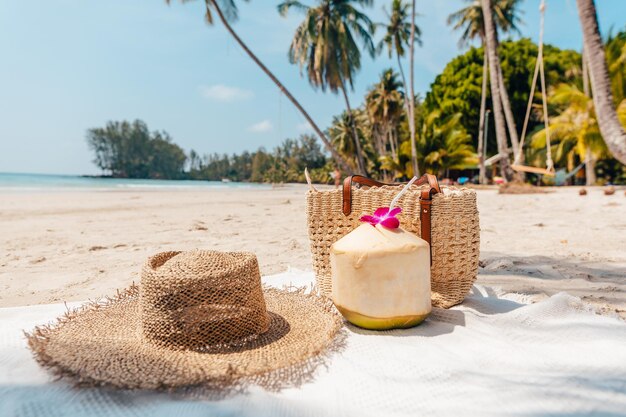 Foto praia e paraíso tropical com um coco descansando na areia e um refrescante coquetel de coco nas proximidades sob palmeiras balançadas