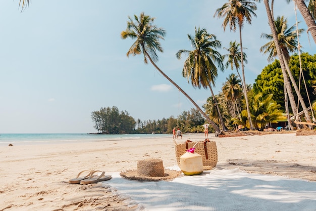 Foto praia e paraíso tropical com um coco descansando na areia e um refrescante coquetel de coco nas proximidades sob palmeiras balançadas