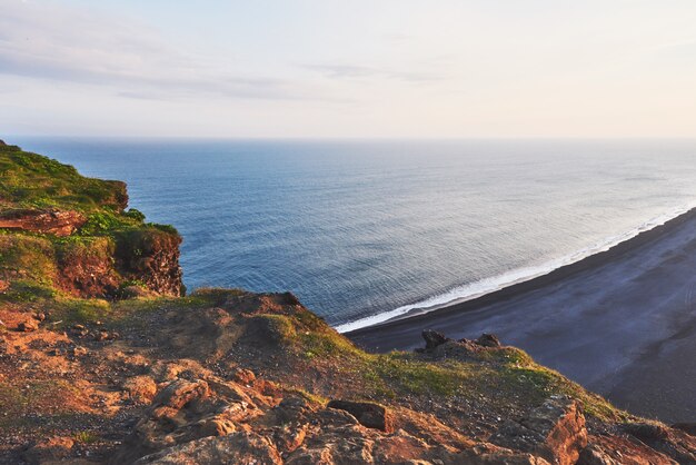 Foto praia fantástica no sul da islândia, lava de areia preta. o pôr do sol pitoresco