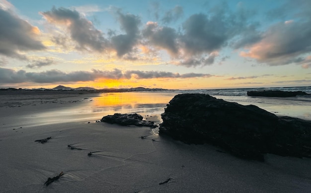 Praia molhada contra o céu do pôr do sol