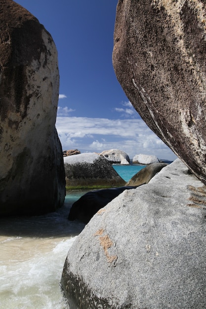 Praia paradisíaca e solitária com grandes pedras e areia fina