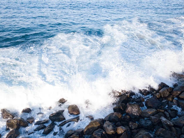 Praia rochosa com ondas do Oceano Atlântico se encontrando com rochas afiadas subaquáticas