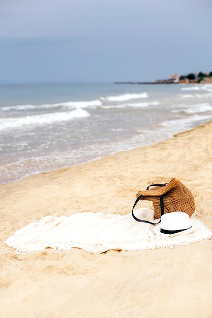 Foto praia sem pessoas com chapéu de palha e saco de praia