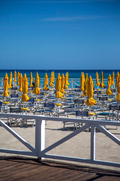 Praia siciliana com espreguiçadeiras e guarda-sóis amarelos