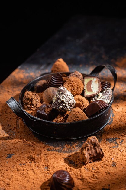 Pralinen in einem Teller auf dunklem Hintergrund Kakao