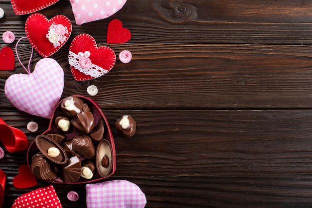 Pralinenschachtel und handgemachte Herzen zum Valentinstag auf Holztisch