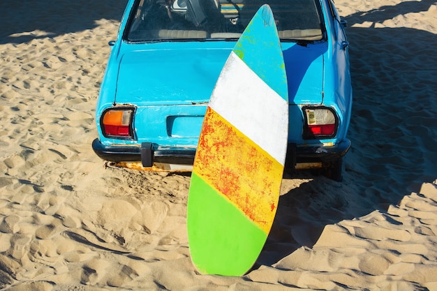 Prancha de surf velha em carro enferrujado à beira-mar.