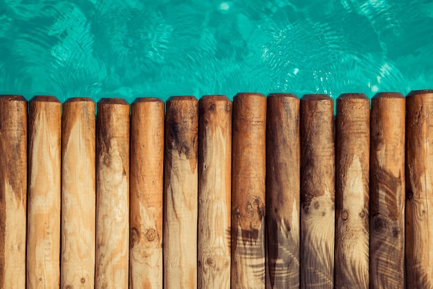 Pranchas de madeira contra água azul Conceito de férias de verão