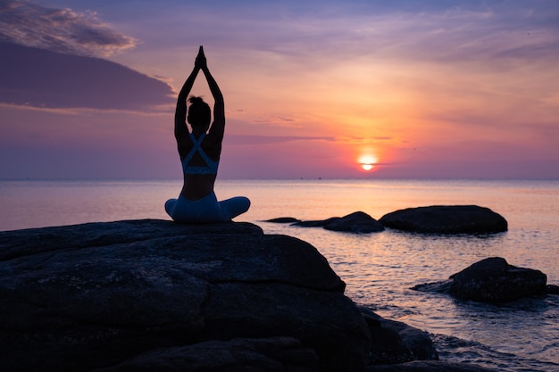 Prática de garota asiática Yoga na praia dia de manhã do nascer do sol