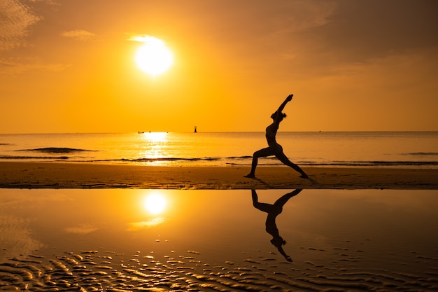 Prática de garota asiática Yoga na praia dia de manhã do nascer do sol