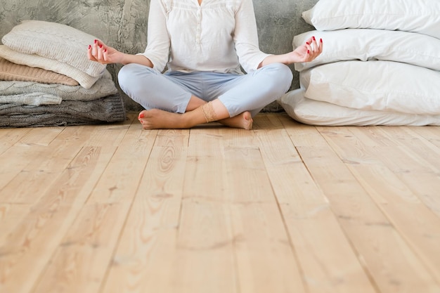 Prática de meditação Conceito de estilo de vida Mulher sentada no chão de madeira de pernas cruzadas com mãos de mudra