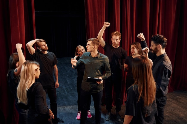 Foto prática em andamento grupo de atores em roupas de cor escura em ensaio no teatro