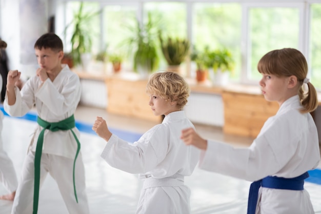 Praticando Aikido. Meninos e meninas de quimono branco e cintos coloridos praticando Aikido