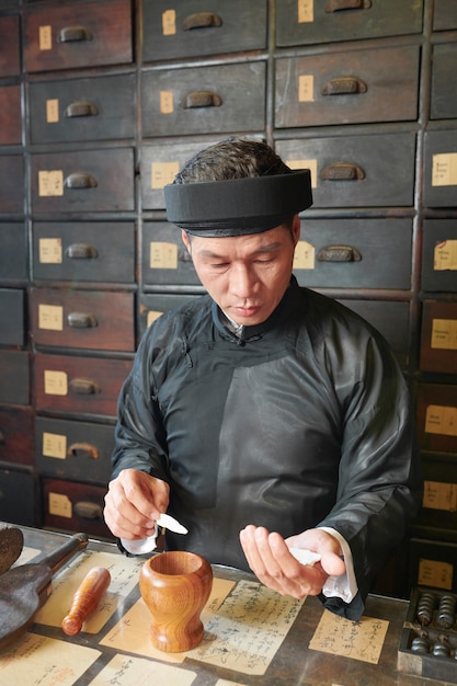 Praticante de medicina chinesa colocando cogumelo seco no pilão