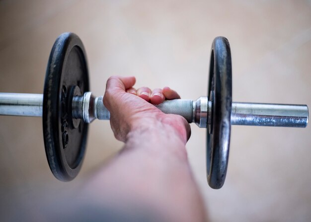 Foto pratique esportes em casa. cortar a vista de uma mão segurando um peso do haltere