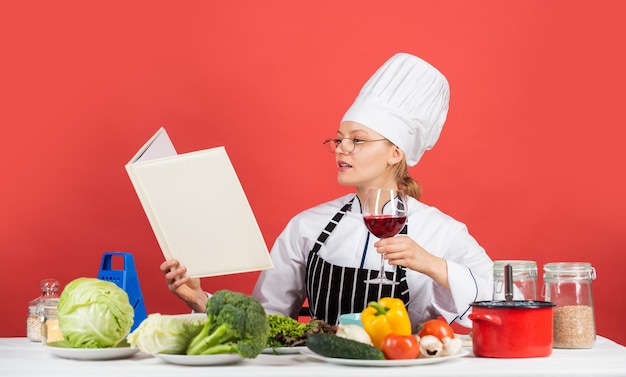 Pratique mais. chef profissional lê a receita para cozinhar. chef feminina preparando o prato. cozinhar em sua cozinha. Abra o livro de receitas para uma culinária saudável. mantém um segredo sobre os ingredientes. mulher usa o livro de receitas.