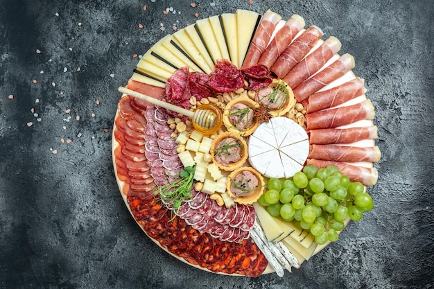 Foto prato antipasto carnes frias com uvas presunto jamon carne seca chouriço salame fuet patê e mel camembert queijo de cabra aperitivo conceito de festa catering banner menu receita