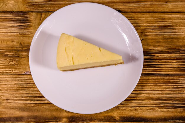 Prato branco com cheesecake New York na mesa de madeira rústica. Vista do topo
