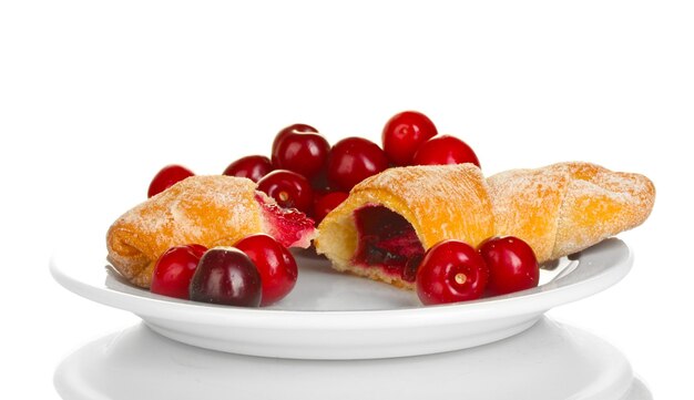 Prato branco com croissant e cereja isolado em branco