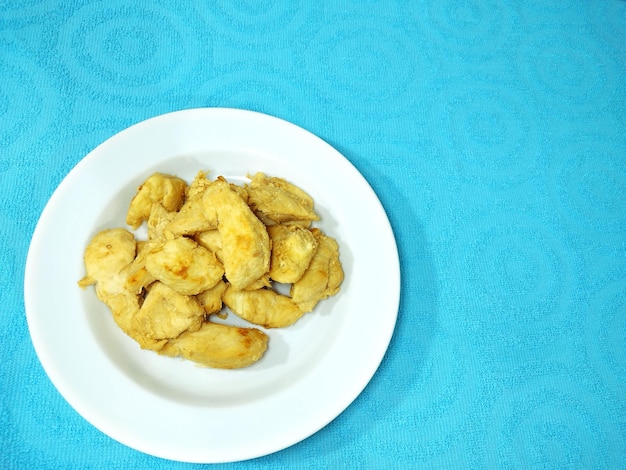 Foto prato branco com filé de peito de frango no forro de mesa azul decorado