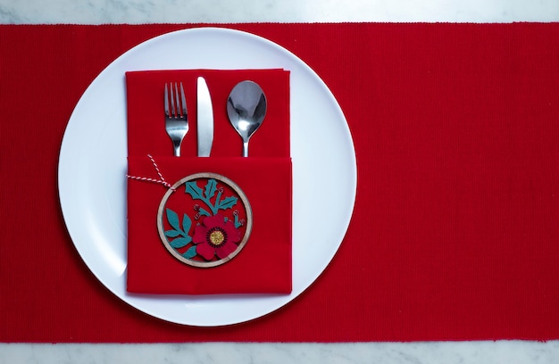 Prato branco com talheres, na mesa vermelha, conceito de configurações de natal, horizontal, sem pessoas. Foto de alta qualidade