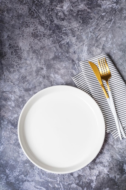 Prato branco vazio com guardanapo para receita de comida e restaurante de menu na mesa de pedra e fundo escuro. Vista do topo. Projeto liso.