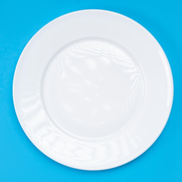 Foto prato branco vazio em um fundo azul vista superior