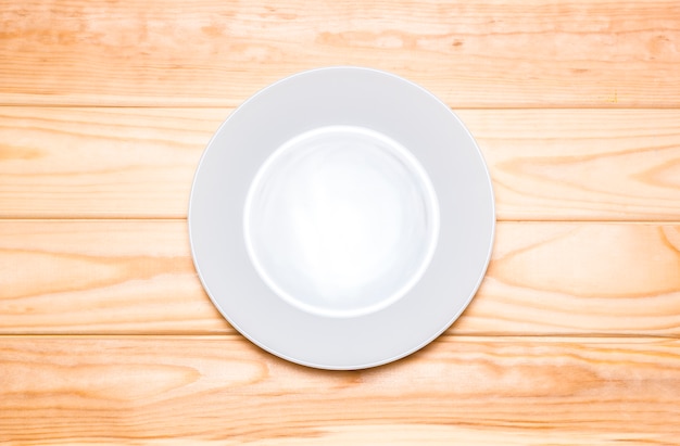 Prato branco vazio em uma mesa de madeira