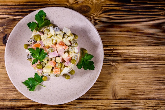 Prato cerâmico com salada tradicional russa de ano novo olivier em uma mesa de madeira Vista superior