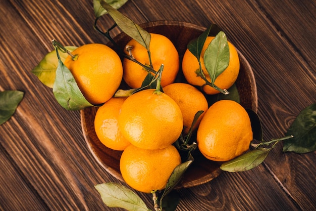 Prato com algumas tangerinas na mesa de madeira