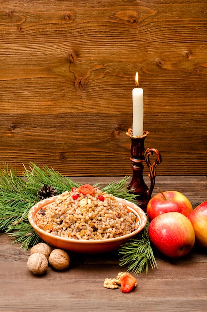 Prato com as tradicionais iguarias eslavas de Natal na véspera de Natal. Ramo de abeto, maçãs e velas em um fundo de madeira