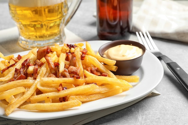 Prato com batatas fritas e bacon na mesa