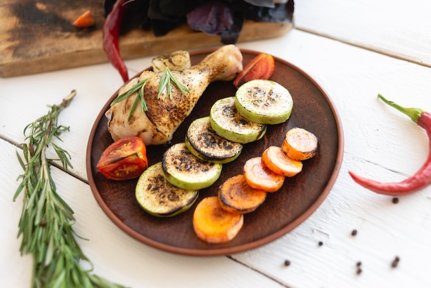 Prato com comida na mesa, legumes grelhados e coxa de frango