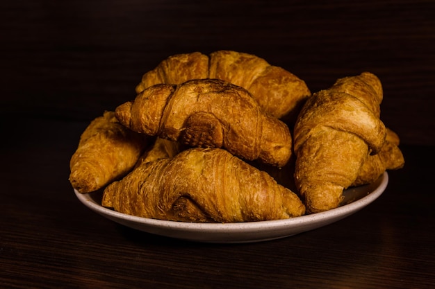 Prato com croissants frescos em uma mesa de madeira escura