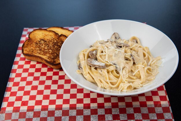 Prato com delicioso fettuccine de frango alfredo na mesa preta