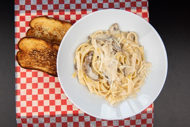 Prato com delicioso fettuccine de frango alfredo na mesa preta