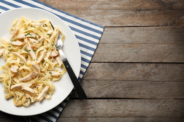 Prato com delicioso Frango Alfredo na mesa de madeira