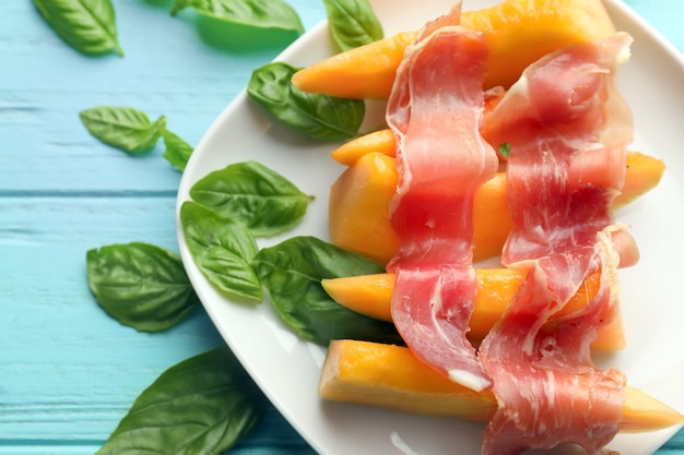 Prato com delicioso melão e presunto na mesa de cores