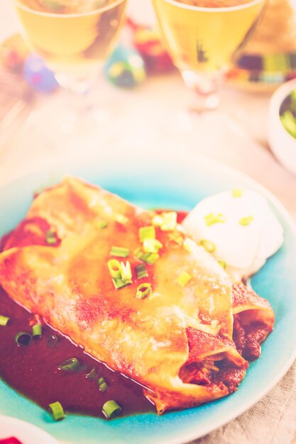 Prato com enchiladas de Frango guarnecido com cebolinha e creme de leite.