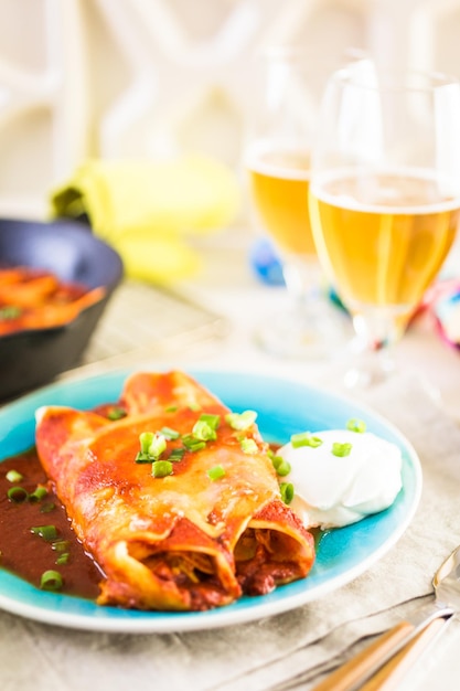 Prato com enchiladas de Frango guarnecido com cebolinha e creme de leite.