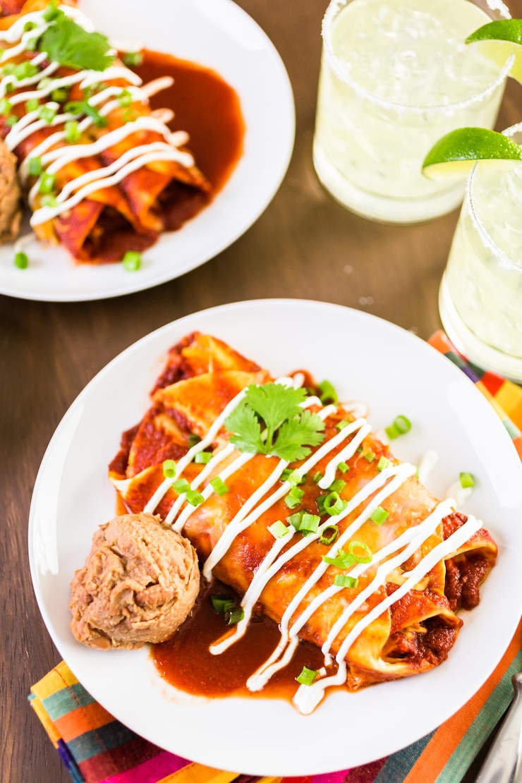 Foto prato com enchiladas de frango guarnecido com cebolinha e creme de leite.