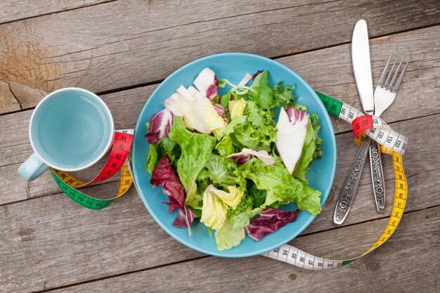 Prato com faca e garfo de xícara de fita métrica de salada fresca Comida dietética