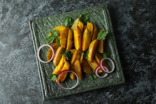 Prato com fatias de batata, salsa e cebola em fundo preto esfumaçado