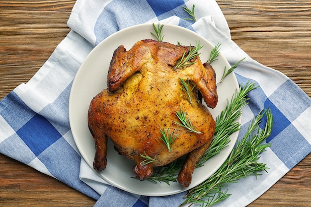 Prato com frango assado de lata de cerveja em fundo de madeira