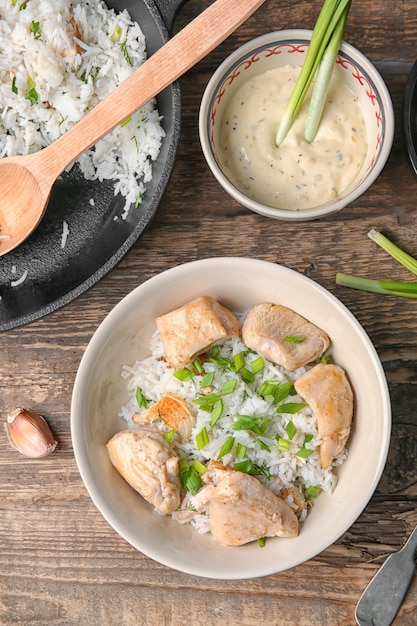 Prato com frango saboroso e arroz na mesa de madeira