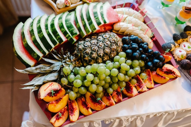 Prato com fruta. Mesa de sobremesas decorada para festa: frutas e guloseimas. Doces deliciosos no buffet.