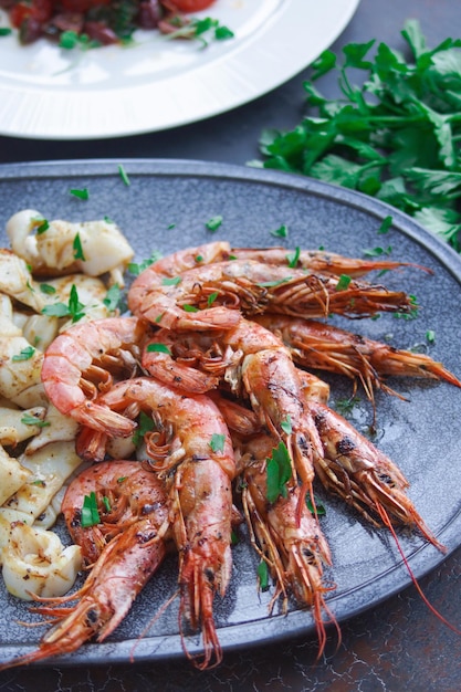 Prato com frutos do mar, camarões e lulas, menu de peixe no restaurante, fundo escuro