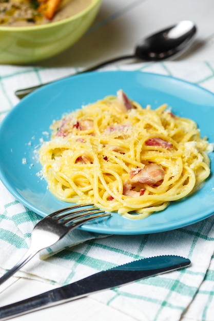 Prato com macarrão carbonara e talheres