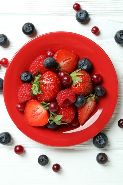 Prato com mistura de frutas silvestres em fundo branco de madeira